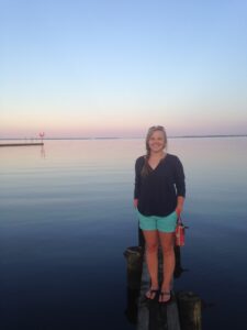 Danielle Adams photo standing on a dock with a body of water in the background.